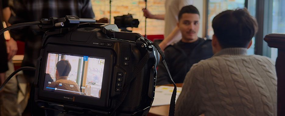 Vue sur un bar avec deux personnes assises et une caméra affichant ces deux personnes