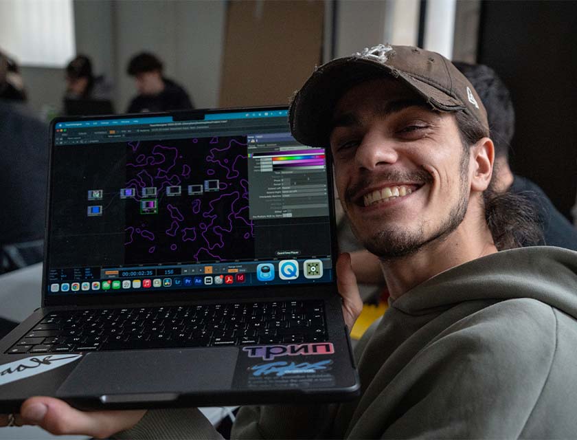 un étudiant montrant son ordinateur et son travail avec un grand sourire