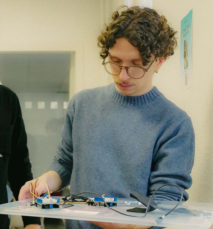 Vue sur un intervenant tenant une planche avec des objets Arduino.
