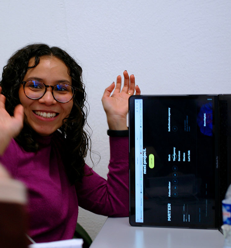Photo d'une étudiante souriante avec son ordi placé sur le côté.