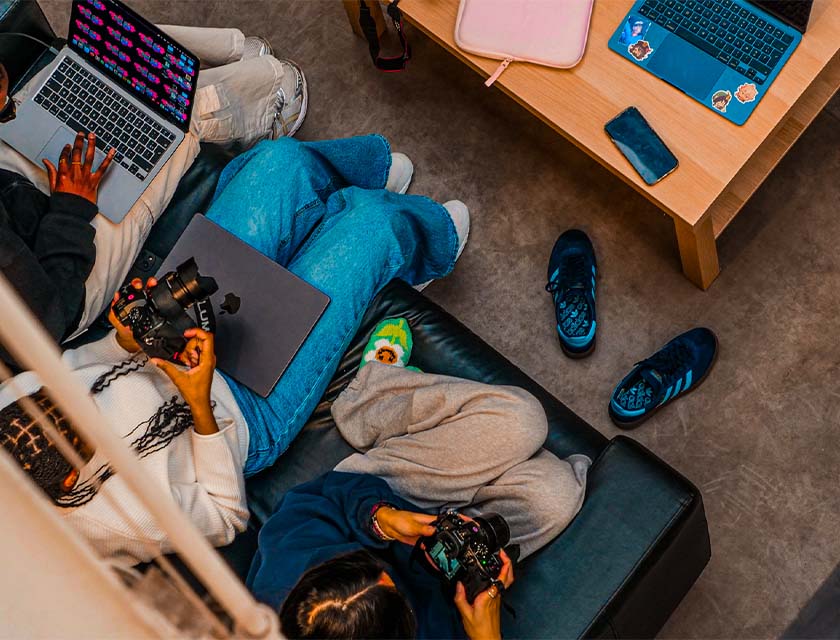 Vue de haut sur des étudiantes assises dans un canapé, appareils photo à la main