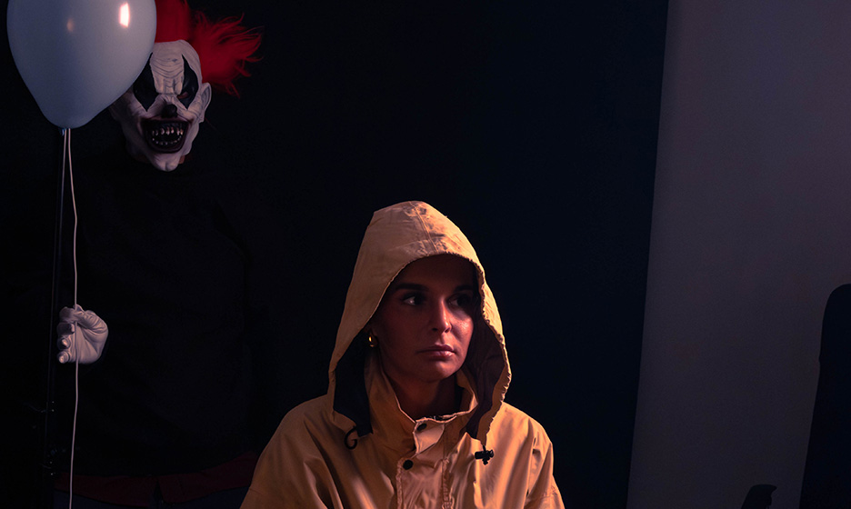 Étudiant déguisé avec un manteau jaune et un portant le costume de Ça, tenant un ballon