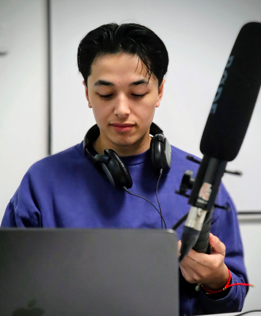 Étudiant se préparant en tenant son micro et regardant son ordi