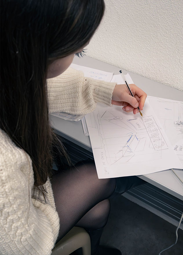 Vue sur une étudiante qui dessine sur une feuille.